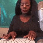 a woman is typing on a computer keyboard next to a microphone .