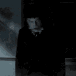 a person is standing in a dark room with a smoke coming out of their mouth .