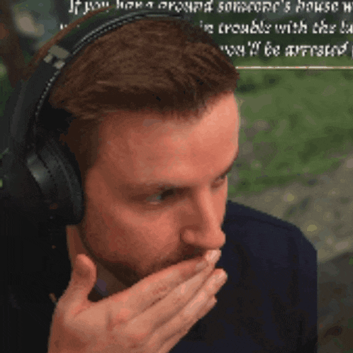 a man wearing headphones covering his mouth with his hands