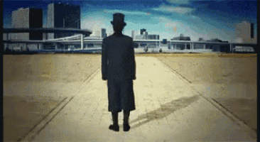 a silhouette of a man in a top hat standing in front of a city