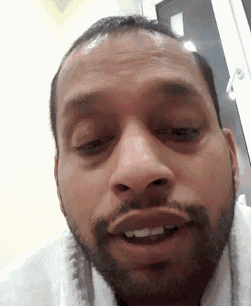 a man with a beard and a white towel around his neck is smiling