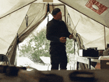 a man standing in a tent holding a sword