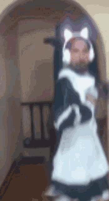 a man wearing a maid costume and headphones is standing in a room .