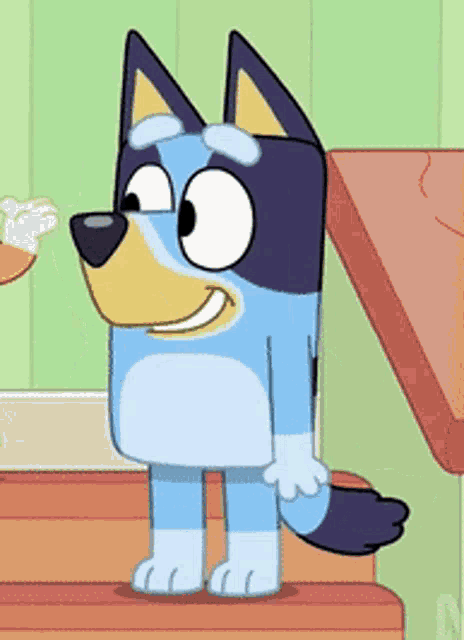 a blue and yellow cartoon dog is standing on a wooden table and smiling .
