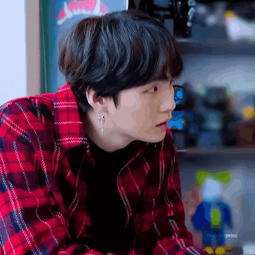 a close up of a person wearing a plaid shirt and earring .