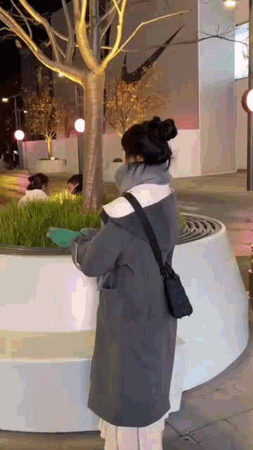 a woman wearing a gray coat is standing in front of a nike logo