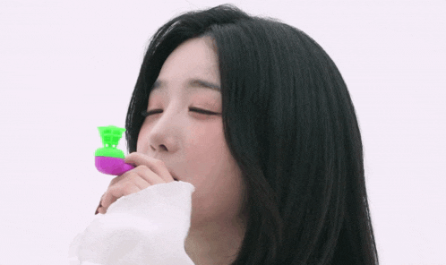 a woman blowing soap bubbles with a green and purple object in her mouth