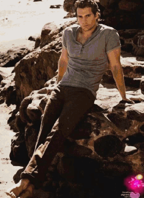 a man is sitting on a rock on the beach