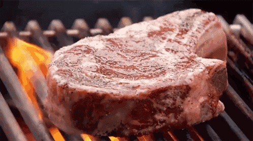 a large piece of meat is being cooked on a grill