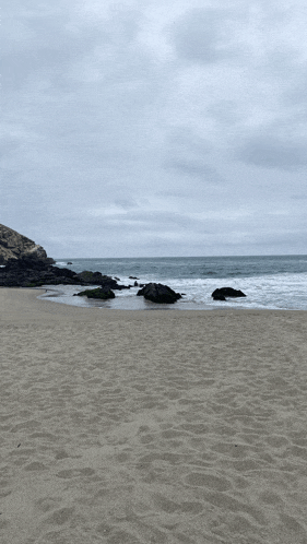 a beach with rocks in the sand and a cloudy sky