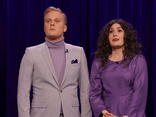 a man in a suit and a woman in a purple dress are standing next to each other