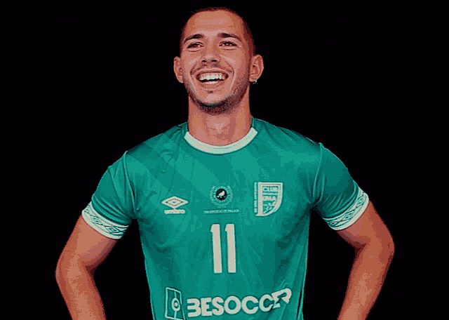 a man wearing a green besoccer jersey is smiling