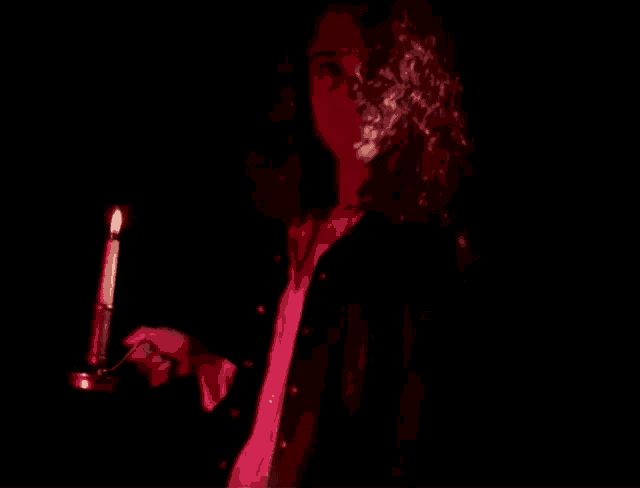 a person holding a candle in the dark