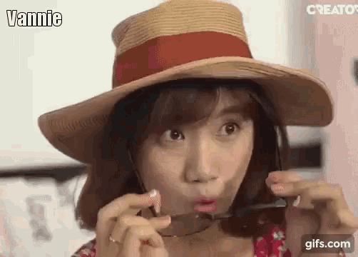 a woman wearing a hat and sunglasses is making a face .
