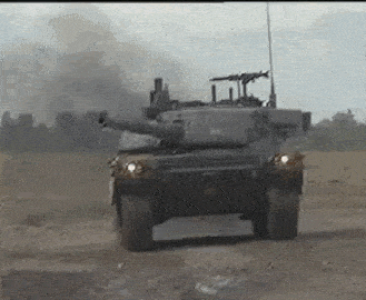 a military tank is driving down a dirt road in the middle of a field .