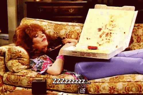 a woman is laying on a couch holding a pizza box and saying zzz