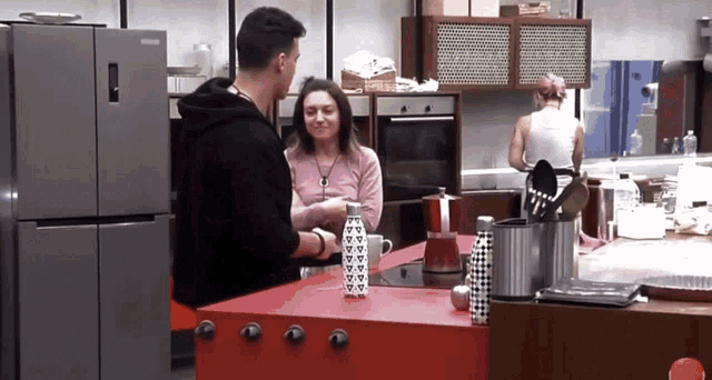 a man and a woman standing in a kitchen with a samsung refrigerator in the background