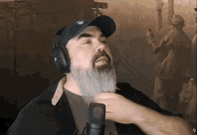 a man with a beard wearing headphones and a hat with the number 9 on the bottom right