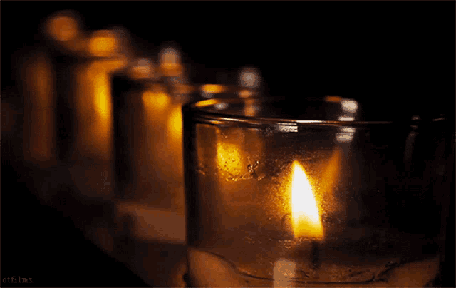 a row of candles are lit up in a dark room with the words otfilms at the bottom