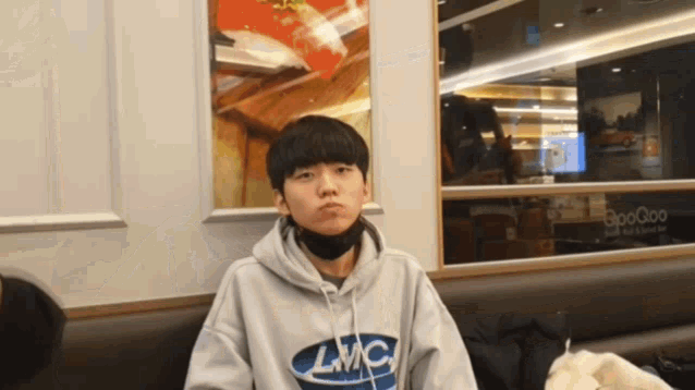 a young man wearing a hoodie that says lmc makes a face