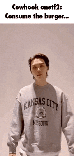a man in a kansas city missouri sweatshirt is standing in front of a white wall .