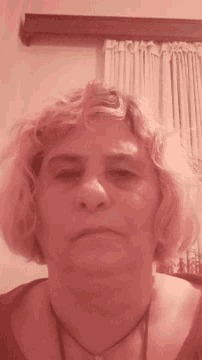 a close up of a woman 's face with a curtain behind her
