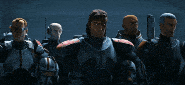 a group of men in armor are standing next to each other in a dark room .