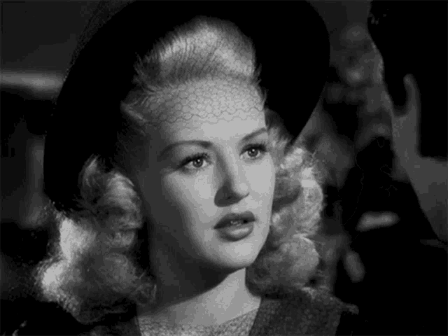 a black and white photo of a blonde woman wearing a black hat