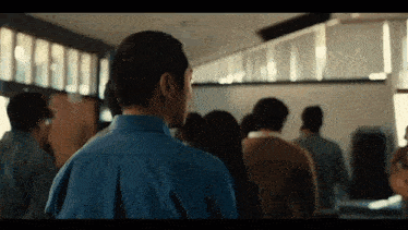 a man in a blue shirt is standing in front of a group of people