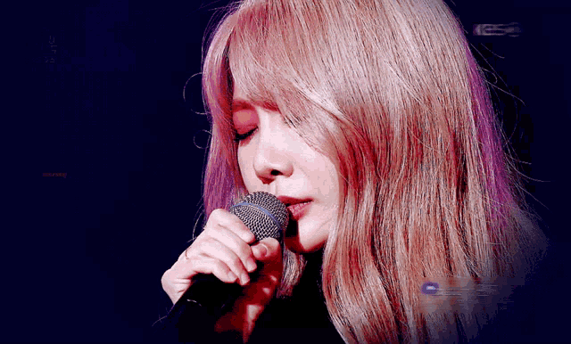 a close up of a woman singing into a microphone with the letters kbs on the bottom right