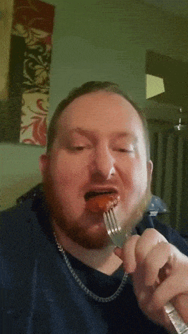 a man with a beard is eating a piece of food with a fork