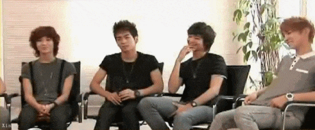 a group of young men are sitting in chairs in a room