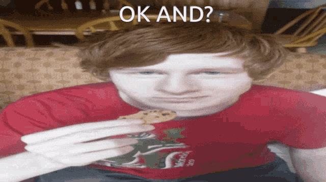 a young man in a red shirt is eating a cookie with the words ok and behind him