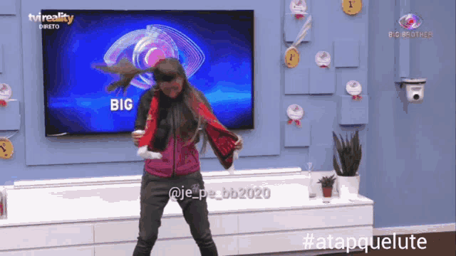 a woman is dancing in front of a big brother tv