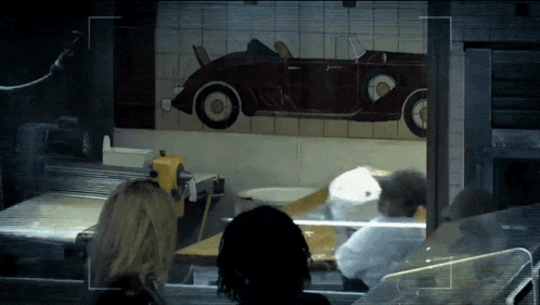 a woman looks out a window at a painting of an old car
