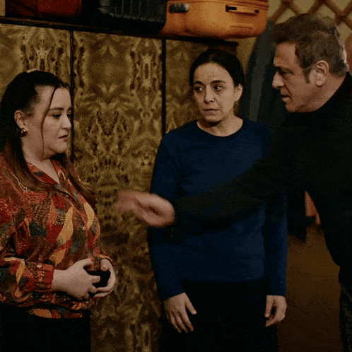 a man and two women are standing next to each other and one of them is talking on a cell phone