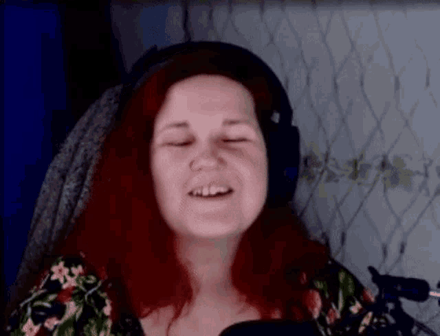 a woman with red hair is wearing headphones and making a funny face .