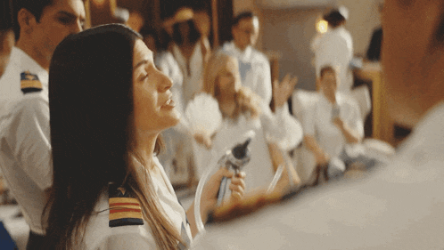 a woman in a white uniform with a gold stripe on the shoulder looks up at something