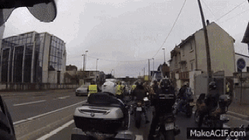 a group of motorcycle riders are driving down a street with makeagif.com at the bottom of the screen