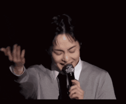 a man is holding a microphone in his hand and singing into it in a dark room .