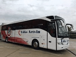 a large white and red bus is parked on the side of the road .