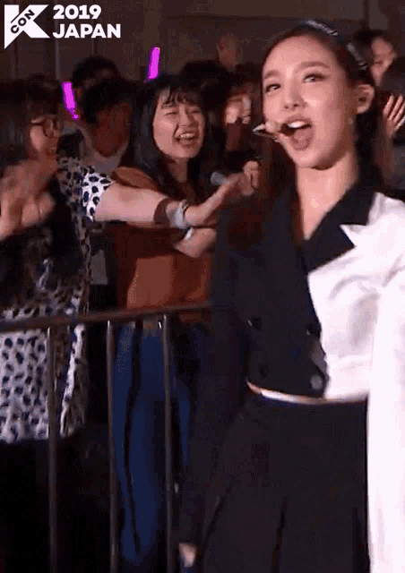 a woman is standing in front of a crowd of people in a crowded room .