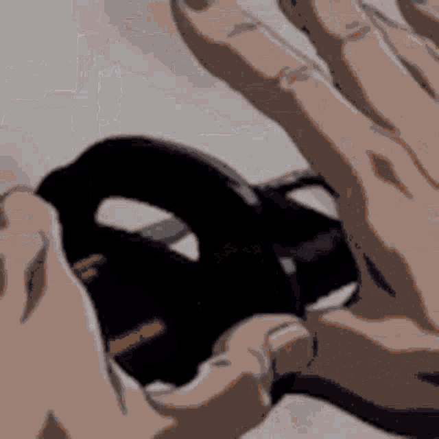 a close up of a person 's hand holding a black object