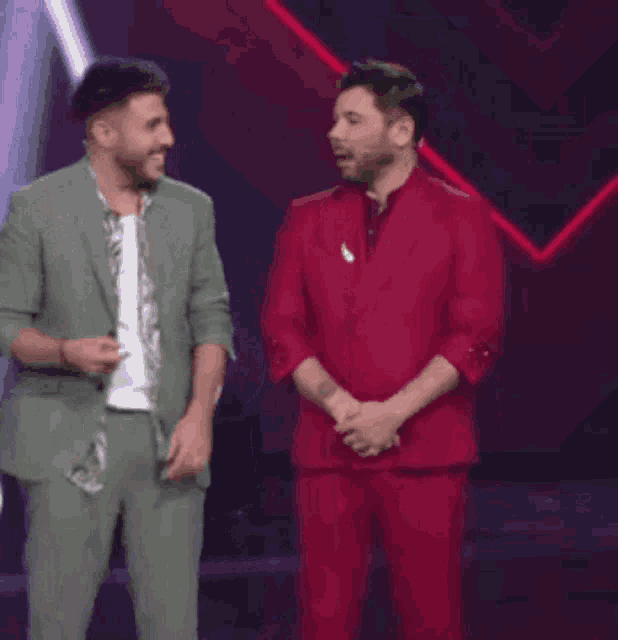 a man in a red suit is standing next to another man in a green suit