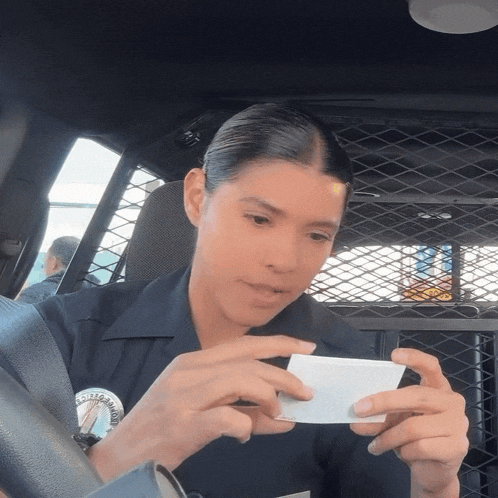 a woman in a police uniform is holding a piece of paper that says " california " on it