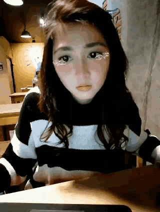 a woman wearing a black and white striped sweater looks at the camera