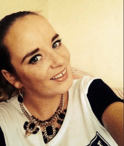 a woman wearing a black and white shirt and a necklace smiles