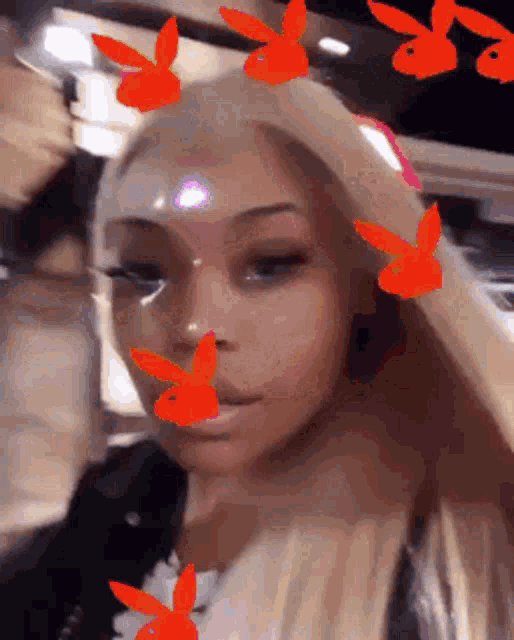 a woman with long blonde hair and red playboy bunny stickers on her face .