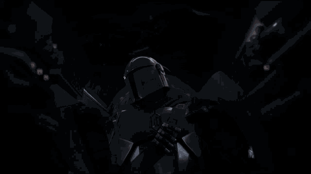 a man in a helmet stands in the dark with his hands folded