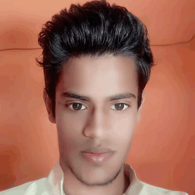 a close up of a young man 's face against an orange wall